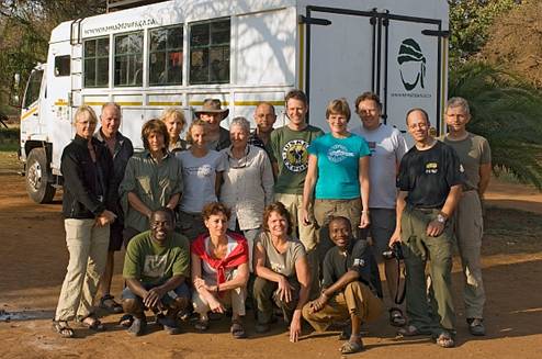 Ons reisgezelschap. Op de hurken links kok Shadi. Op de hurken rechts Dudu de chauffeur.Op de achtergrond is Tommy, onze truck
